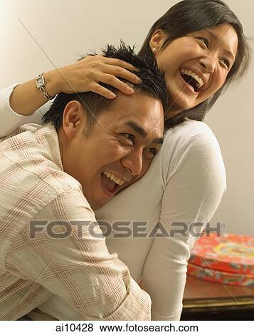 Stock Photo - Man hugging woman, laughing. Fotosearch