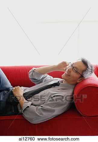 Man in shirt and tie, lying on sofa, using mobile phone View Large Photo Image Stock Image - Man in shirt and tie, lying on sofa, using mobile phone. Fotosearch