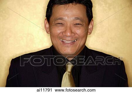 Stock Image - Man in suit and tie, looking at camera, smiling. Fotosearch