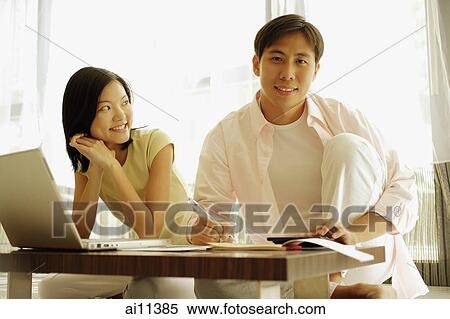 Man looking at camera, woman looking at him, laptop open in front of them View Large Photo Image Stock Photography - Man looking at camera, woman looking at him, laptop open in front of them. Fotosearch