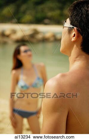 Picture - Man looking away, woman in the background. Fotosearch