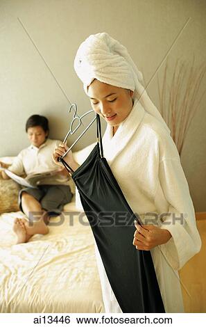 Man lying on bed, woman in robe holding dress View Large Photo Image Stock Photograph - Man lying on bed, woman in robe holding dress. Fotosearch