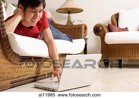 Man lying on sofa, using laptop, head on hand View Large Photo Image Stock Photography - Man lying on sofa, using laptop, head on hand. Fotosearch