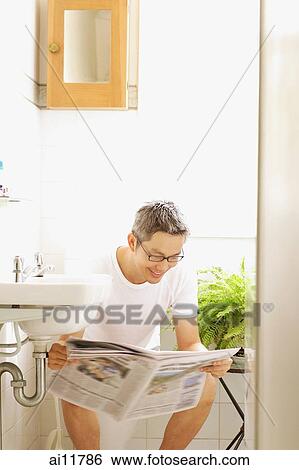 Stock Photograph - Man on toilet, reading newspaper. Fotosearch
