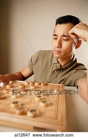 Man playing Chinese chess, hand on head View Large Photo Image Stock Photo - Man playing Chinese chess, hand on head. Fotosearch