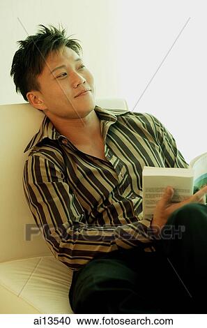 Man sitting, holding book, looking away View Large Photo Image Stock Image - Man sitting, holding book, looking away. Fotosearch