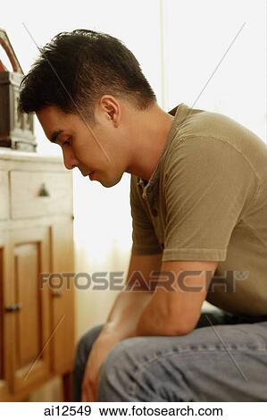 Stock Photo - Man sitting, looking down. Fotosearch