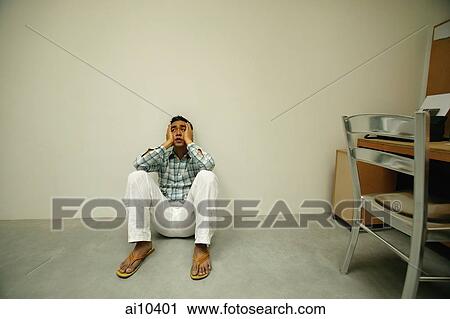 Man sitting on floor, hands on face, looking worried View Large Photo Image Stock Image - Man sitting on floor, hands on face, looking worried. Fotosearch