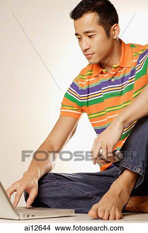 Man sitting on floor using laptop View Large Photo Image Picture - Man sitting on floor using laptop. Fotosearch