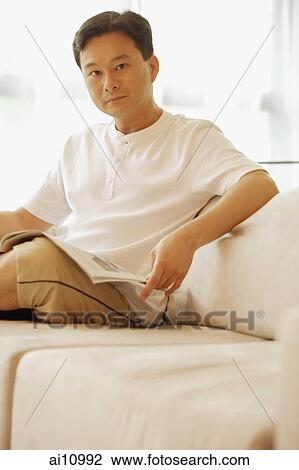 Man sitting on sofa, looking at camera View Large Photo Image Stock Image - Man sitting on sofa, looking at camera. Fotosearch