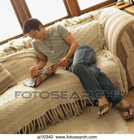 Man sitting on sofa, reading magazine View Large Photo Image Stock Image - Man sitting on sofa, reading magazine. Fotosearch