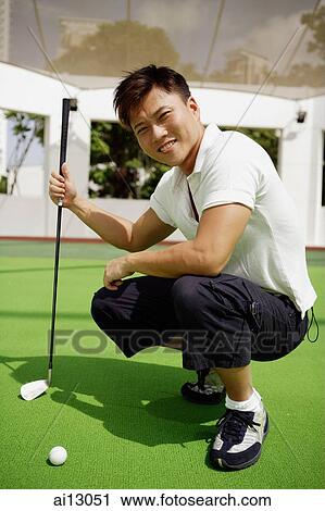 Man squatting down, holding golf club, looking at camera View Large Photo Image Stock Image - Man squatting down, holding golf club, looking at camera. Fotosearch