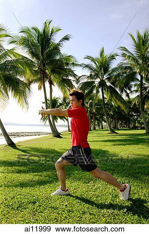 Man stretching in park, wearing red shirt View Large Photo Image Stock Photo - Man stretching in park, wearing red shirt. Fotosearch