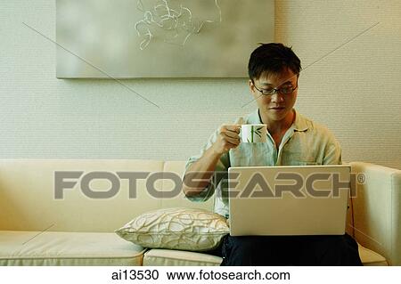 Man using laptop and holding cup View Large Photo Image Stock Image - Man using laptop and holding cup. Fotosearch