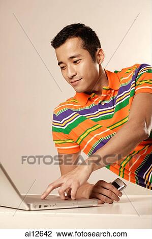 Man using laptop and holding mobile phone View Large Photo Image Stock Image - Man using laptop and holding mobile phone. Fotosearch