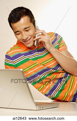 Man using laptop and using mobile phone View Large Photo Image Stock Image - Man using laptop and using mobile phone. Fotosearch