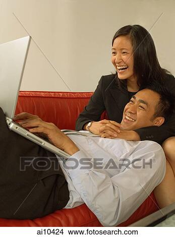 Man using laptop, woman hugging him View Large Photo Image Picture - Man using laptop, woman hugging him. Fotosearch