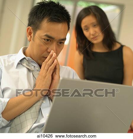 Stock Photograph - Man using laptop, woman watching him. Fotosearch