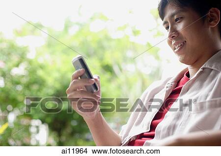 Man using mobile phone, text messaging, smiling View Large Photo Image Picture - Man using mobile phone, text messaging, smiling. Fotosearch