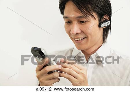 Stock Image - Man using PDA, smiling. Fotosearch