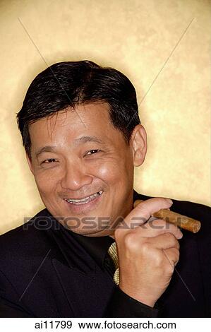 Stock Photo - Man with cigar looking at camera, smiling. Fotosearch