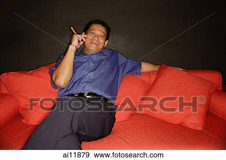 Man with cigar, lounging on sofa View Large Photo Image Stock Photo - Man with cigar, lounging on sofa. Fotosearch