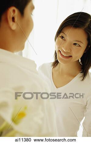 Man with flowers behind his back, facing woman View Large Photo Image Stock Image - Man with flowers behind his back, facing woman. Fotosearch