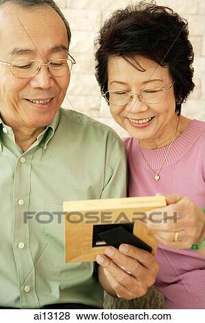 Mature couple, looking at picture frame View Large Photo Image Stock Photo - Mature couple, looking at picture frame. Fotosearch