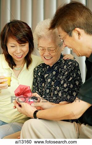 Mature couple with older woman, holding gift box View Large Photo Image Stock Image - Mature couple with older woman, holding gift box. Fotosearch