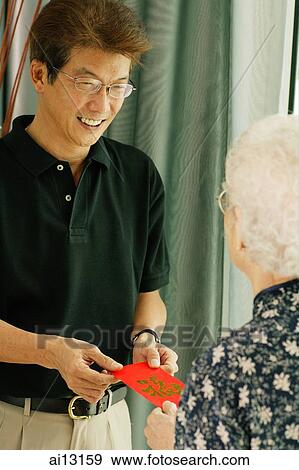 Mature man giving red packet to a senior woman View Large Photo Image Stock Photo - Mature man giving red packet to a senior woman. Fotosearch