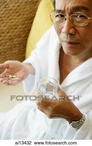 Mature man holding glass of water and pills View Large Photo Image Stock Image - Mature man holding glass of water and pills. Fotosearch