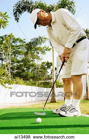 Stock Photo - Mature man holding golf club. Fotosearch