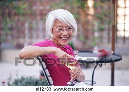 Mature woman holding wine glass, looking at camera View Large Photo Image Stock Image - Mature woman holding wine glass, looking at camera. Fotosearch