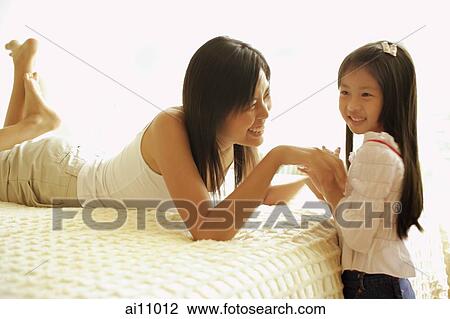 Stock Image - Mother and daughter in bedroom, face to face. Fotosearch