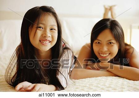 Mother and daughter lying on bed, looking at camera View Large Photo Image Stock Image - Mother and daughter lying on bed, looking at camera. Fotosearch