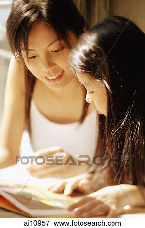 Mother and daughter, side by side, looking at magazine View Large Photo Image Stock Photo - Mother and daughter, side by side, looking at magazine. Fotosearch