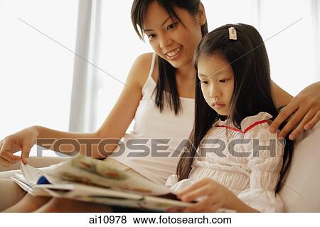 Mother and daughter, sitting side by side, looking at book View Large Photo Image Stock Photo - Mother and daughter, sitting side by side, looking at book. Fotosearch