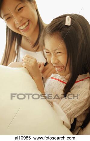 Stock Photography - Mother and daughter, sitting side by side, laughing. Fotosearch