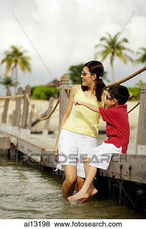 Mother and son, sitting on jetty, boy pointing View Large Photo Image Stock Photo - Mother and son, sitting on jetty, boy pointing. Fotosearch
