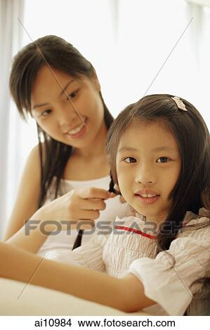 Mother braiding her daughter's hair. View Large Photo Image Picture - Mother braiding her daughter's hair.. Fotosearch