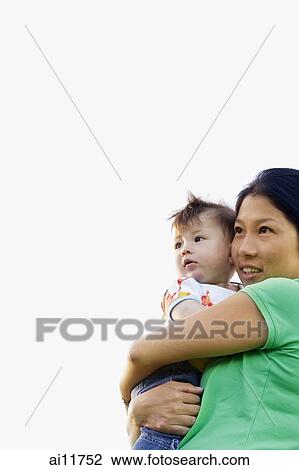 Stock Image - Mother carrying baby girl, low angle view. Fotosearch