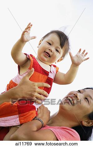 Mother carrying baby girl, low angle view View Large Photo Image Stock Photo - Mother carrying baby girl, low angle view. Fotosearch