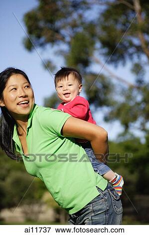 Mother carrying baby girl on her back, sideview View Large Photo Image Stock Photo - Mother carrying baby girl on her back, sideview. Fotosearch