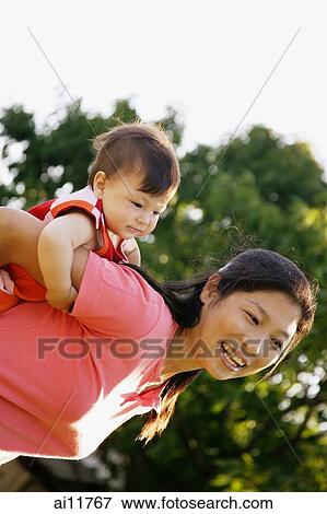 Mother carrying baby girl on her back View Large Photo Image Stock Photo - Mother carrying baby girl on her back. Fotosearch