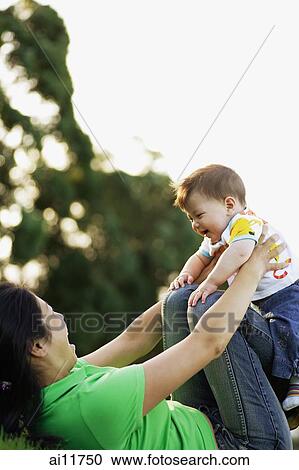 Stock Image - Mother holding baby girl against her knees. Fotosearch