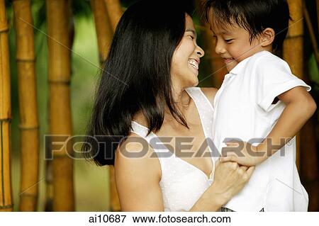 Stock Photo - Mother holding her son, bamboo canes in the background. Fotosearch