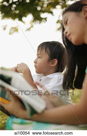 Mother reading a magazine, young boy next to her looking away. View Large Photo Image Picture - Mother reading a magazine, young boy next to her looking away.. Fotosearch