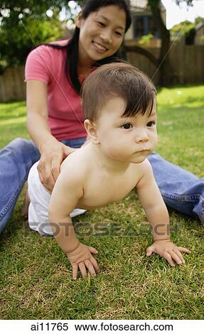 Mother sitting on grass, baby girl crawling away View Large Photo Image Stock Photography - Mother sitting on grass, baby girl crawling away. Fotosearch
