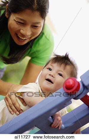 Mother supporting baby girl, baby girl holding ladder View Large Photo Image Stock Photo - Mother supporting baby girl, baby girl holding ladder. Fotosearch
