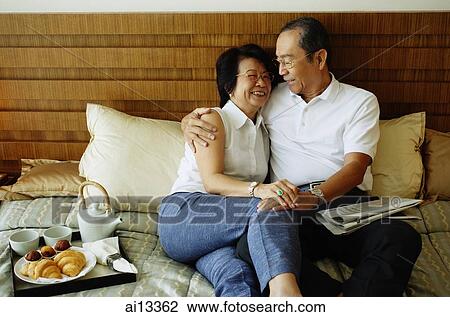 Stock Image - Older couple lying on bed, hugging. Fotosearch